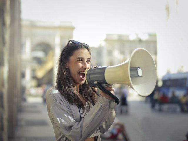 Picture of a woman happily shouting into a megaphone