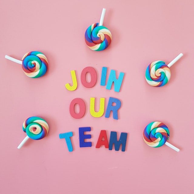 The words 'JOIN OUR TEAM' spelled out with magnetic letters. Multi colored lollipops surround the words.