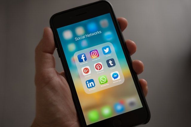 Zoomed in picture of a person's hand holding a phone that is displaying their social networking apps